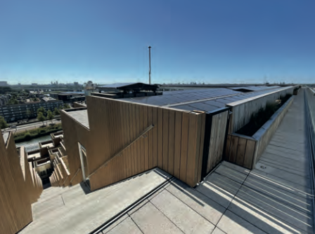 Dachansicht eines modernen Gebäudes mit Holzfassade und Solarpanels unter blauem Himmel